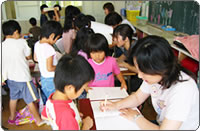 写真(ひらがなの書き方や算数の筆算で子どもの横で支援する。)